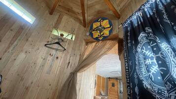 Un intérieur en bois, avec un plafond en bois, un luminaire suspendu et un rideau à motifs.