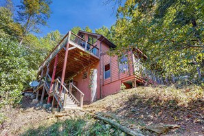 A rustic cabin with a wooden staircase leading to a balcony, surrounded by trees. - Mountain House, Mountain Views, Hot Tub, Game Room, Pool Table, Pinball, Decks & BBQ (Otto)