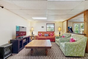 A living room with a television, sofa, and a wooden coffee table. - Mountain House, Mountain Views, Hot Tub, Game Room, Pool Table, Pinball, Decks & BBQ (Otto)