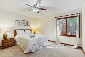 A bedroom with a bed, nightstands, lamps, a ceiling fan, and a window with curtains. - Mountain House, Mountain Views, Hot Tub, Game Room, Pool Table, Pinball, Decks & BBQ (Otto)