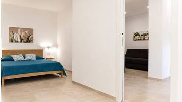 A bedroom with a bed, a bedside table, a wall-mounted lamp, and a painting.