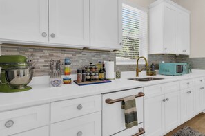 A modern kitchen with white cabinetry, a green stand mixer, a sink, and a teal microwave. - Blue Saffron House - Oasis with Private Pool & Plunge Spa - Historic Sanford (Sanford)