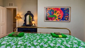 A hotel room with a bed, a dresser, a mirror, a lamp, and a colorful painting on the wall. - Blue Saffron House - Oasis with Private Pool & Plunge Spa - Historic Sanford (Sanford)