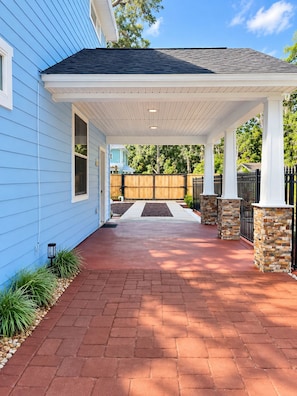 A covered porch with a brick pathway leading to a house with blue siding. - Blue Saffron House - Oasis with Private Pool & Plunge Spa - Historic Sanford (Sanford)