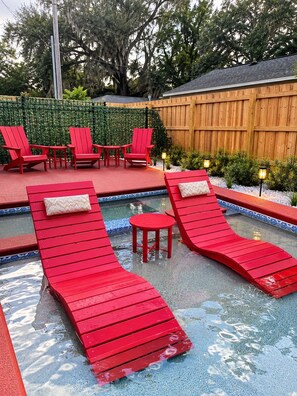 A pool area with red lounge chairs and a small table. - Blue Saffron House - Oasis with Private Pool & Plunge Spa - Historic Sanford (Sanford)