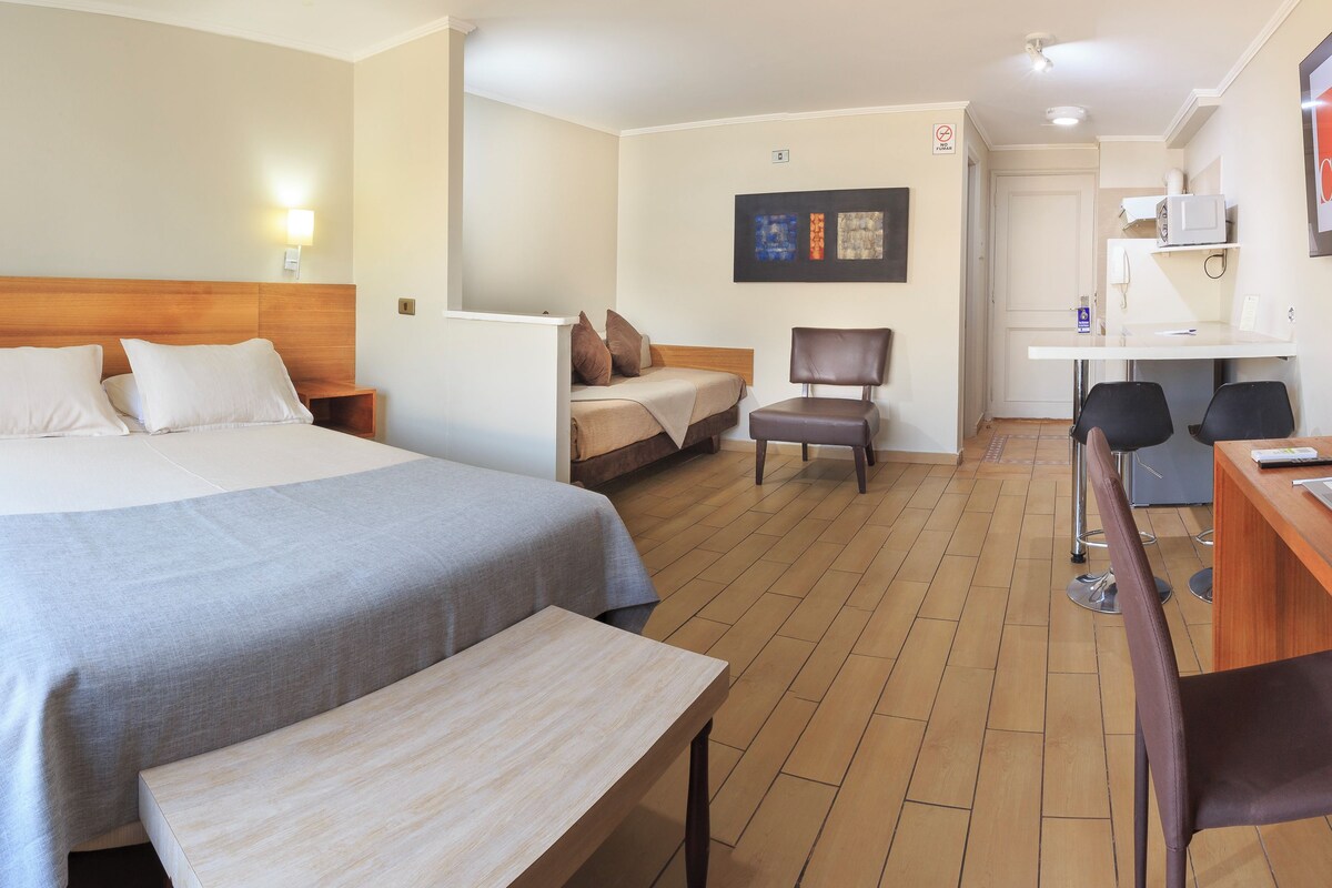 Una habitación de hotel con una cama grande, un escritorio, una silla y una mesita.