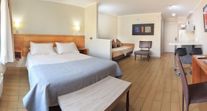 Una habitación de hotel con una cama grande, un escritorio, una silla y una mesita.