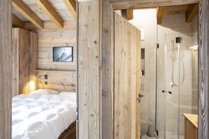 L’intérieur d’un chalet en bois, avec un lit, une douche et un tableau encadré au mur.