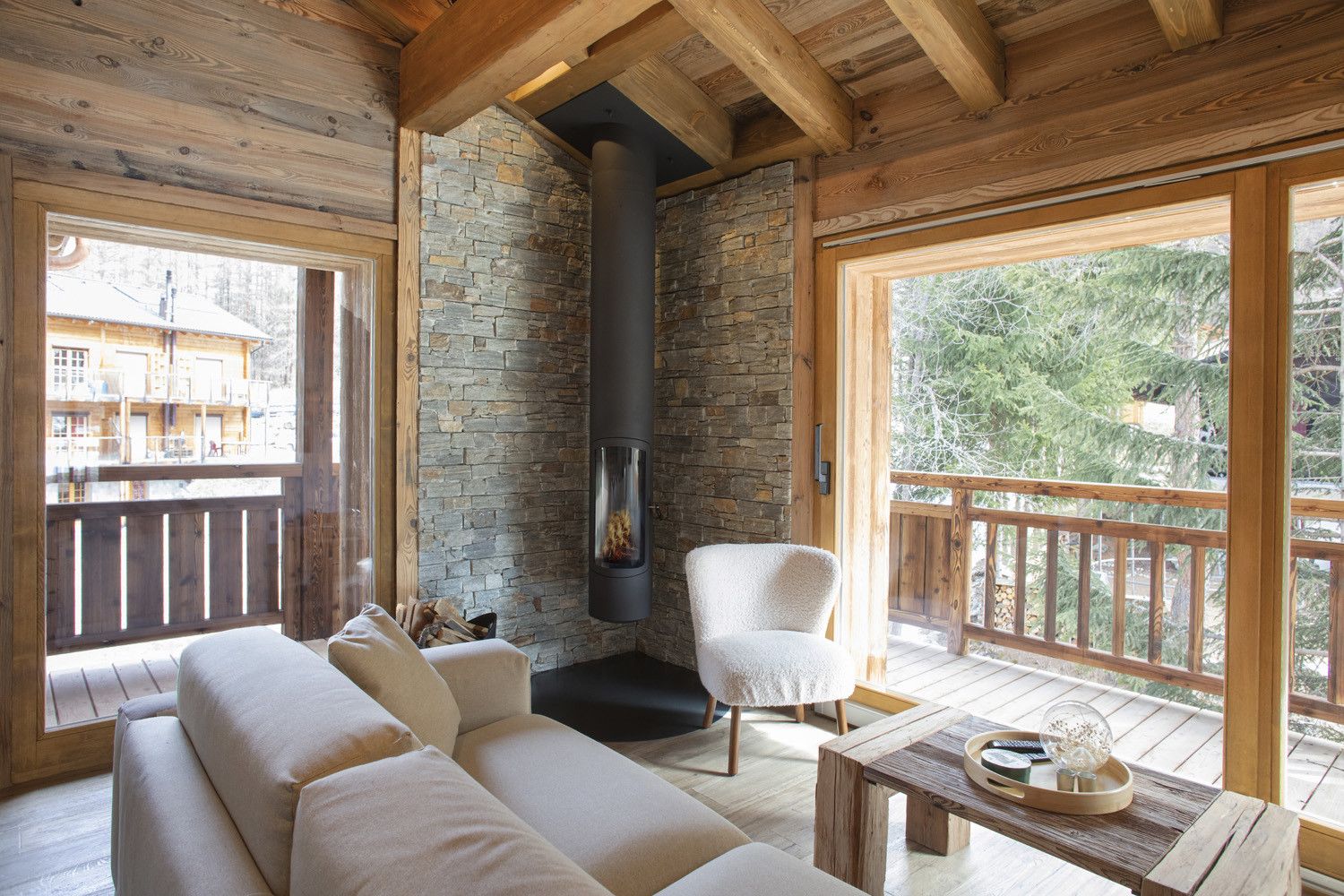 Un intérieur de chalet chaleureux avec un mur en pierre, une cheminée, une terrasse en bois et un canapé.