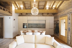A modern kitchen with white cabinets, a central island, and a dining area with a white sofa. - Polaris 1 006 - LUXE & SKI LIFT apartment for 6 people (Zinal)