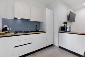 A modern kitchen with white cabinets, a grey backsplash, and a black countertop. - 'Kero House' Apartment with Wi-Fi and Air Conditioning (Alghero)