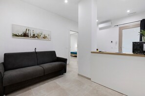 A modern living room with a grey sofa, a coffee table, and a wall-mounted artwork featuring various plants. - 'Kero House' Apartment with Wi-Fi and Air Conditioning (Alghero)