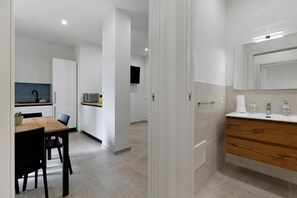 A modern kitchen with a dining area, a built-in TV, and a bathroom with a wooden vanity. - 'Kero House' Apartment with Wi-Fi and Air Conditioning (Alghero)