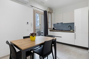 A modern kitchen with a wooden dining table and chairs, a small window, and a view of the outside. - 'Kero House' Apartment with Wi-Fi and Air Conditioning (Alghero)