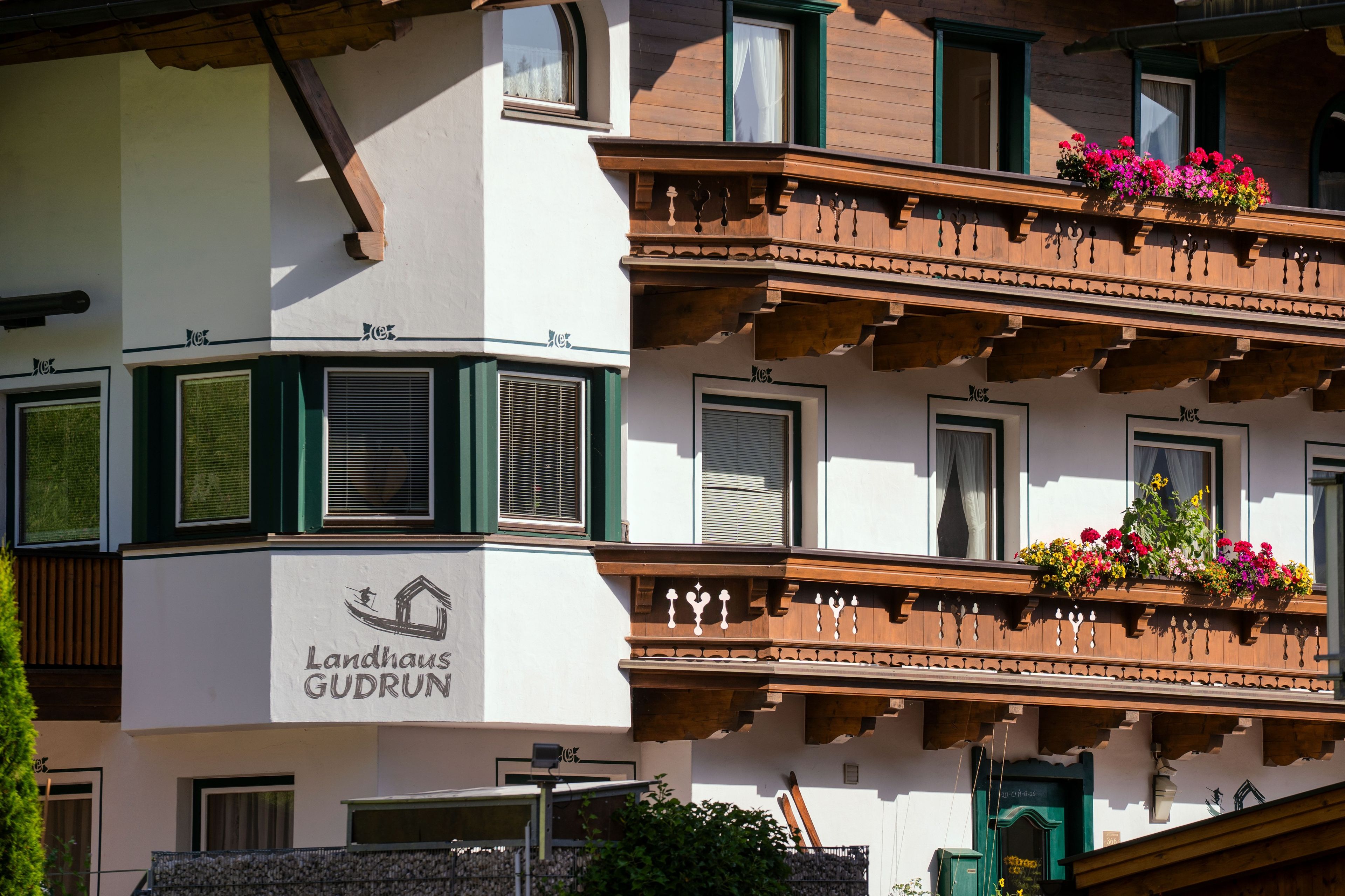 Un edificio con un letrero que dice 'Landhaus Gudrun' y balcones con jardineras florales.