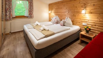 Una camera da letto con una testiera in legno, un letto con molti cuscini, un comodino con un vaso di fiori e una finestra con tende.