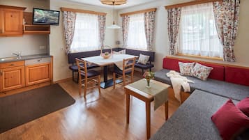 A cozy living area with a dining table, sofa, and a television in the corner.