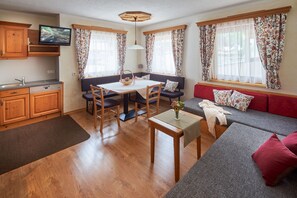 A cozy living area with a dining table, sofa, and a television in the corner. - Ferienwohnung 'Tuxertal' (Tux)