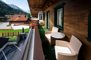A balcony with wicker furniture, a flower arrangement, and a view of a mountain landscape. - Apartment 'Nanno' in Tux (Tux)
