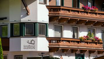 A building with a sign reading 'Landhaus Gudrun' and balconies with flower boxes.