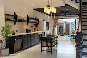 A modern kitchen with a central island, built-in shelves, and a dining area with a table and chairs.