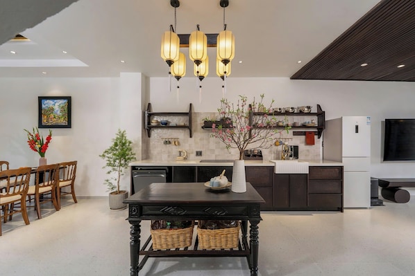 A modern kitchen with a central island, pendant lighting, and a dining area with a table and chairs.