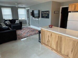 A modern kitchen with a wooden countertop and a television mounted on the wall.