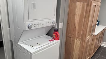 Ein Waschraum mit gestapelten Waschmaschine und Trockner, Holzschränken und einem Fliesenboden.