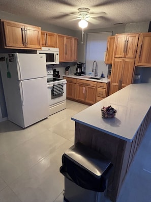A kitchen with wooden cabinets, a refrigerator, a microwave, a stove, and a sink.