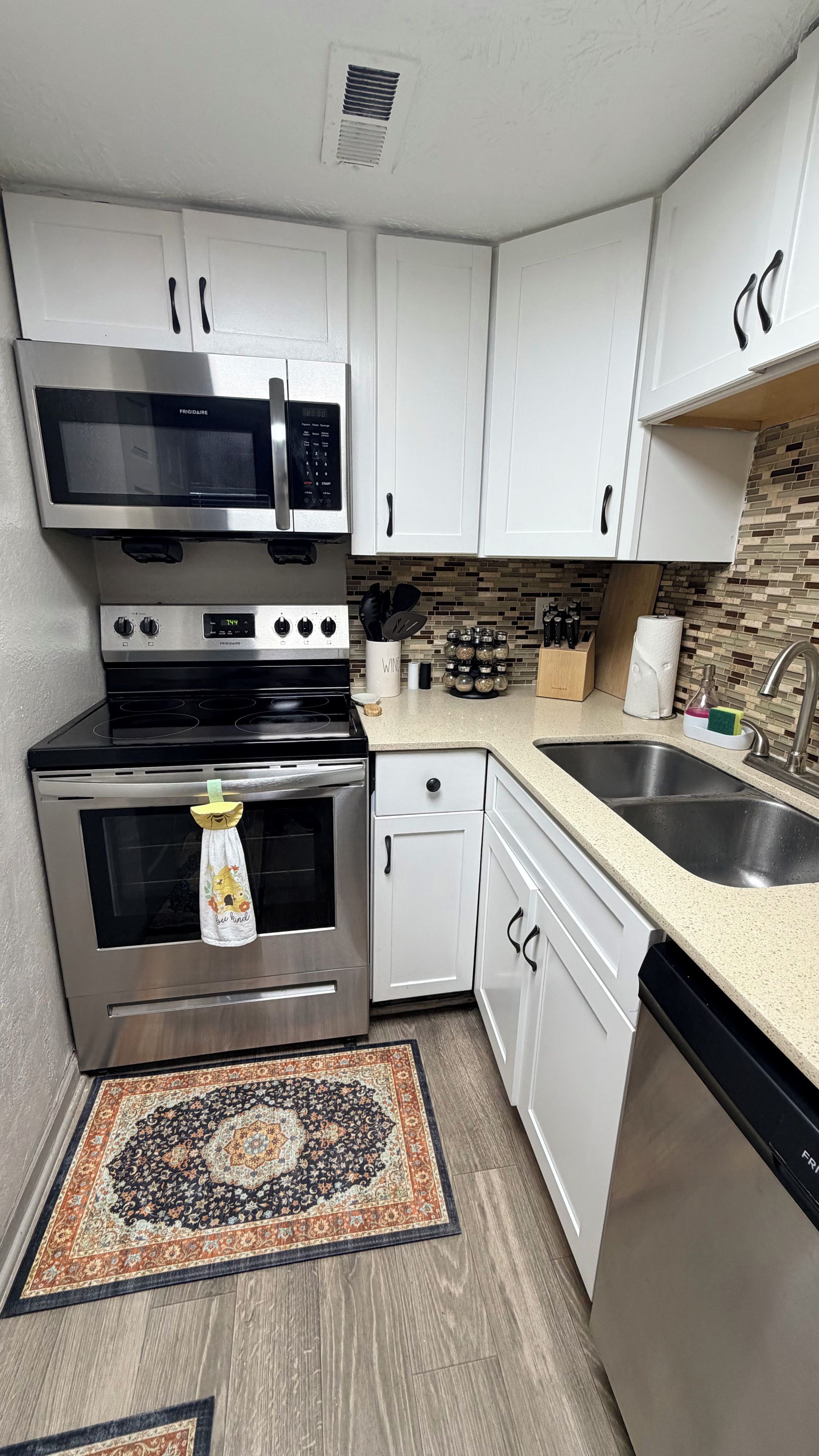Una cocina compacta equipada con microondas, horno, lavavajillas y pileta.