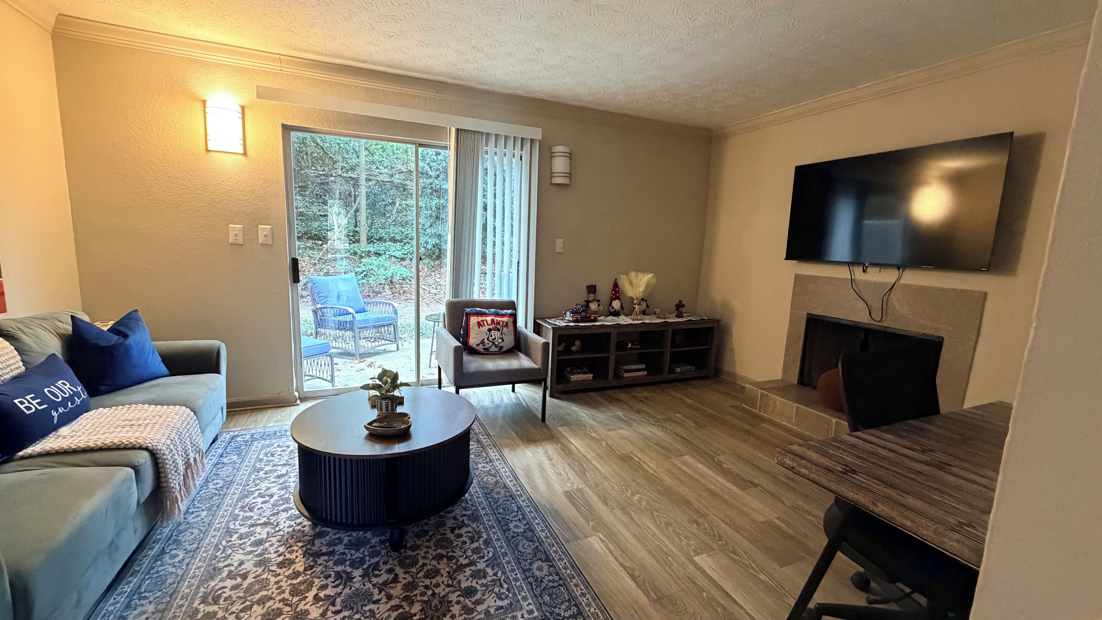 A living room with a sofa, a coffee table, a TV, a fireplace, and a sliding glass door leading to a patio.