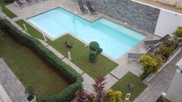 A rectangular outdoor swimming pool with a stone wall and a paved deck area.