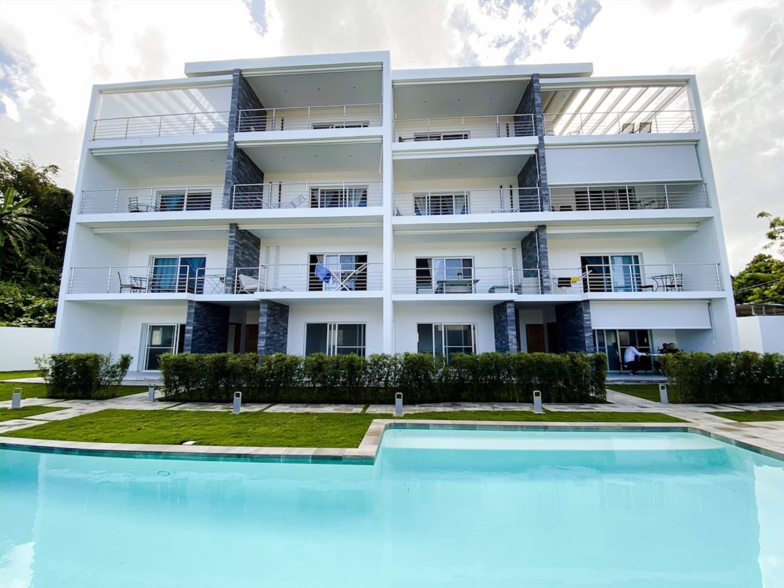 Un edificio residencial de varios pisos con una piscina delantera.