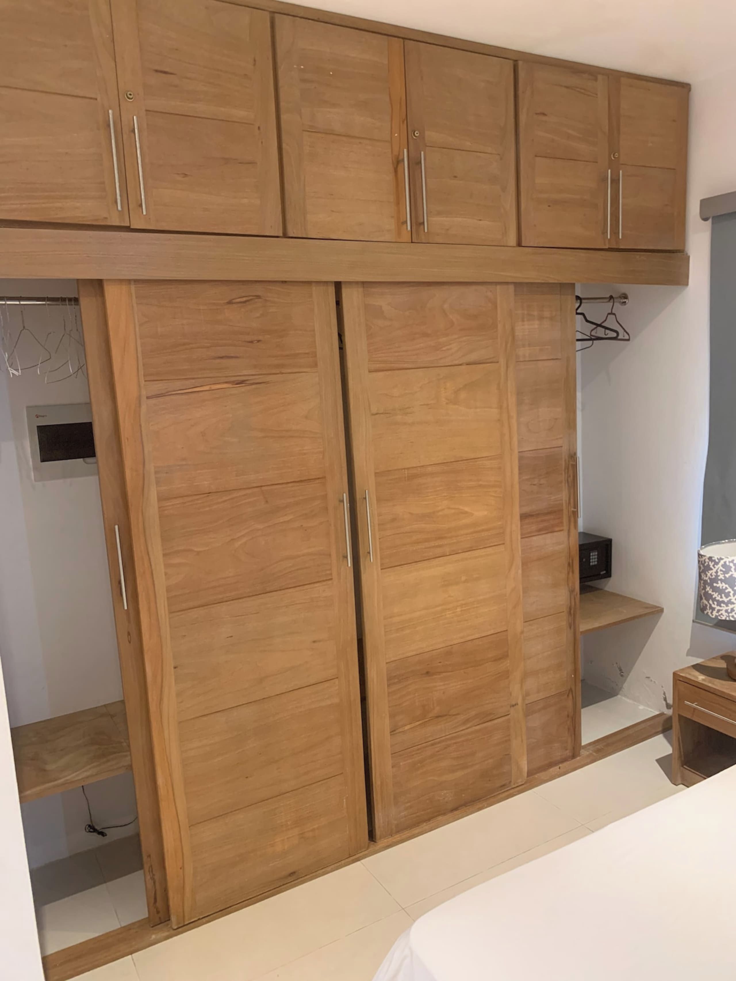 Een slaapkamer met een houten garderobe, een bed en een klein nachtkastje.
