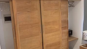 Een slaapkamer met een houten garderobe, een bed en een klein nachtkastje.