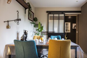 A dining area with a table set for two, chairs, a plant, and a wall-mounted hook.