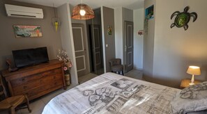 Un dormitorio con cama, cómoda, televisor y lámpara de pared.