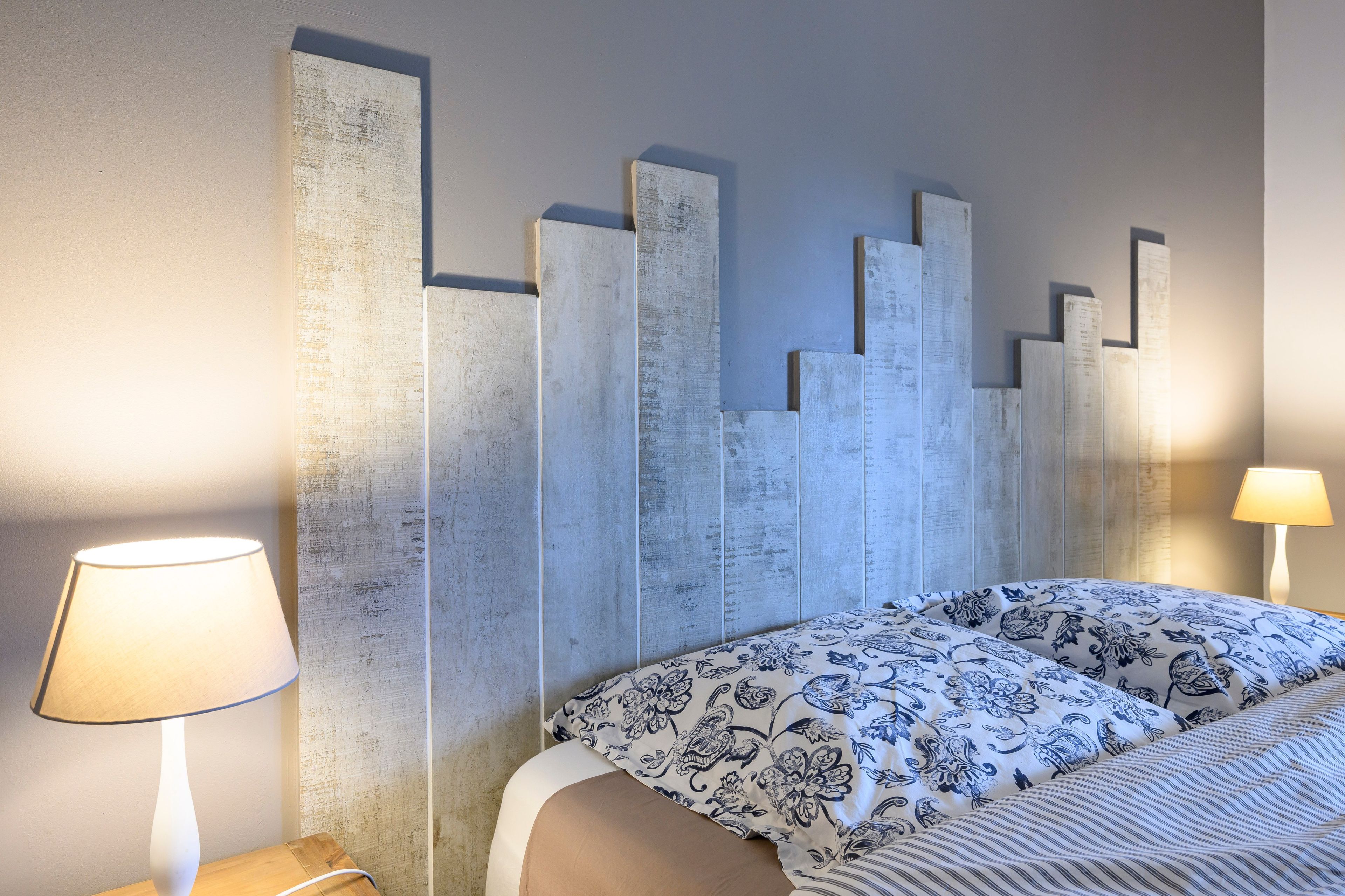 Une chambre à coucher comprenant un lit, une table de chevet, une lampe et un mur au motif texturé.