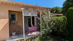 A house with a covered patio, a potted plant, a chair, and a table. - Bed and Breakfast 'Chambre - Le Clos Des Fontaines' with Private Pool, Wi-Fi and Air Conditioning (Pernes-les-Fontaines)
