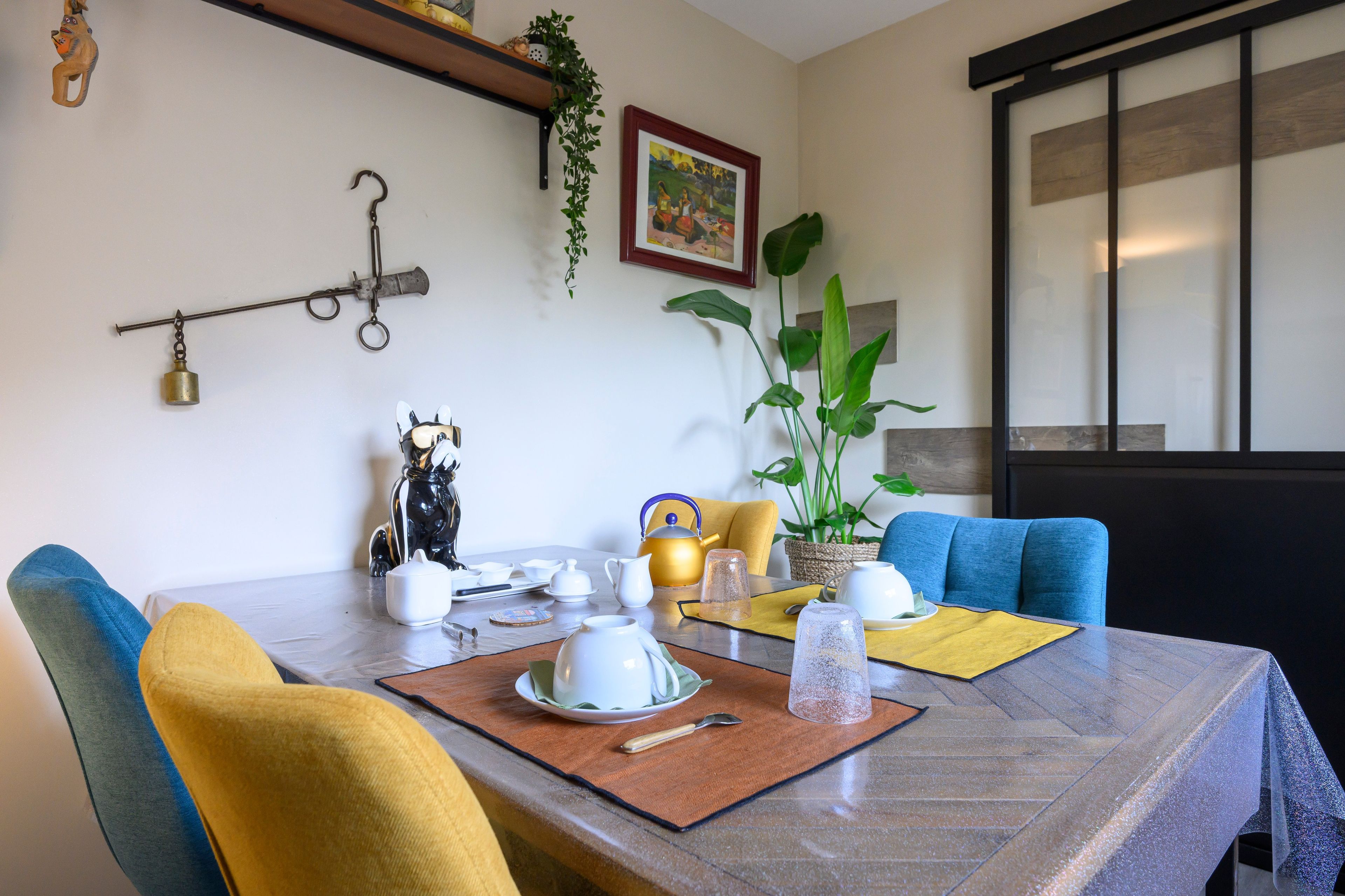 Un coin repas avec une table dressée pour le thé, des chaises et une plante.