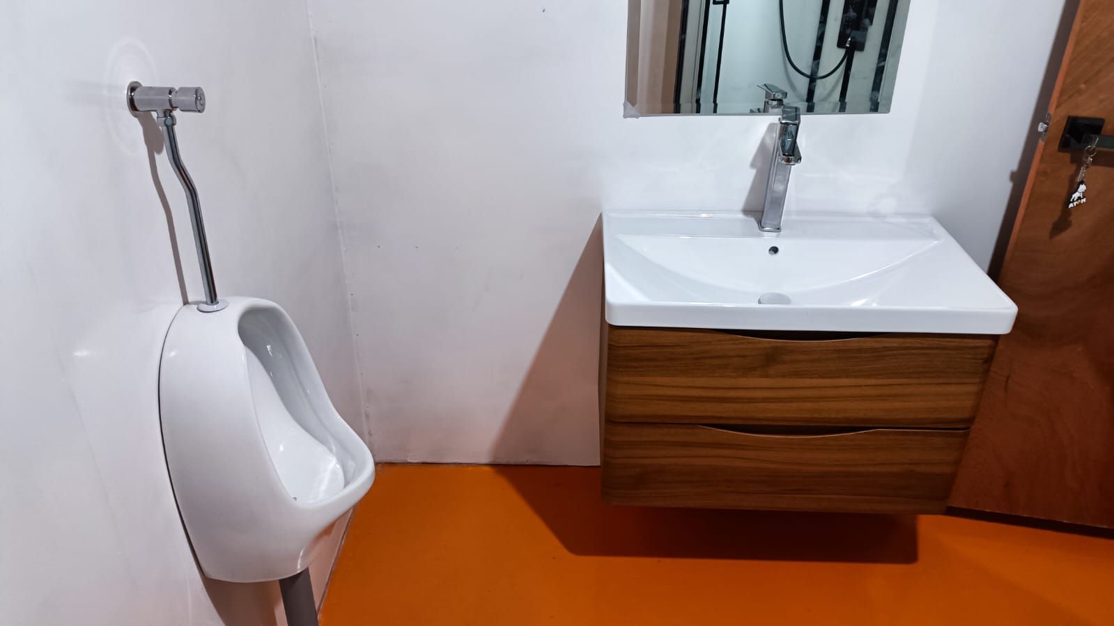 Un orinal, un lavamanos y un armario de madera en un baño.