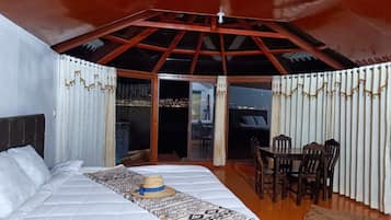 Un dormitorio con cama, una mesa de comedor con sillas y vistas a través de un ventanal.
