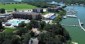 A multi-story hotel with a swimming pool, a dock with boats, and a river view. - Cozy Arnolds Park Cottage with 6 Waterpark Daily Passes Included (Arnolds Park)