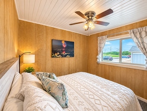 Une chambre à coucher avec un lit, un ventilateur de plafond, une vue sur le ciel étoilé et une fenêtre avec des rideaux.