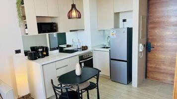 A compact kitchen with a dining area, a microwave, a coffee maker, and a refrigerator.