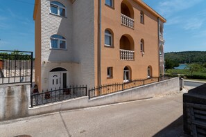 Un edificio de varios pisos con fachada de piedra, ventanas arqueadas y un balcón con barandilla.