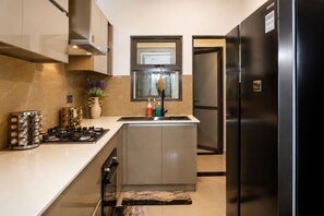 A modern kitchen with a built-in gas stove, stainless steel appliances, and a large refrigerator. - Luxury Golf Retreat At Canterbury Lexus Golf Resort (Gonapola)