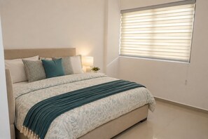 A bedroom with a bed, pillows, a bedside lamp, and a window with blinds. - Luxury Golf Retreat At Canterbury Lexus Golf Resort (Gonapola)