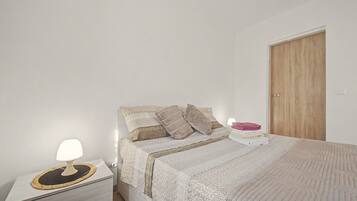 Quarto com cama, mesa de cabeceira e uma porta de madeira.