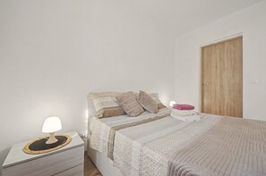A bedroom with a bed, a bedside table with a lamp, and a wooden door. - 'Nel Borghetto' Apartment with Shared Terrace, Balcony, and Wi-Fi (Ivrea)